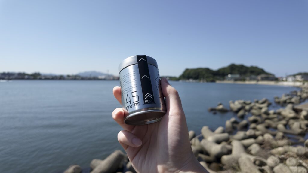 海辺で手に持った缶と周囲の風景